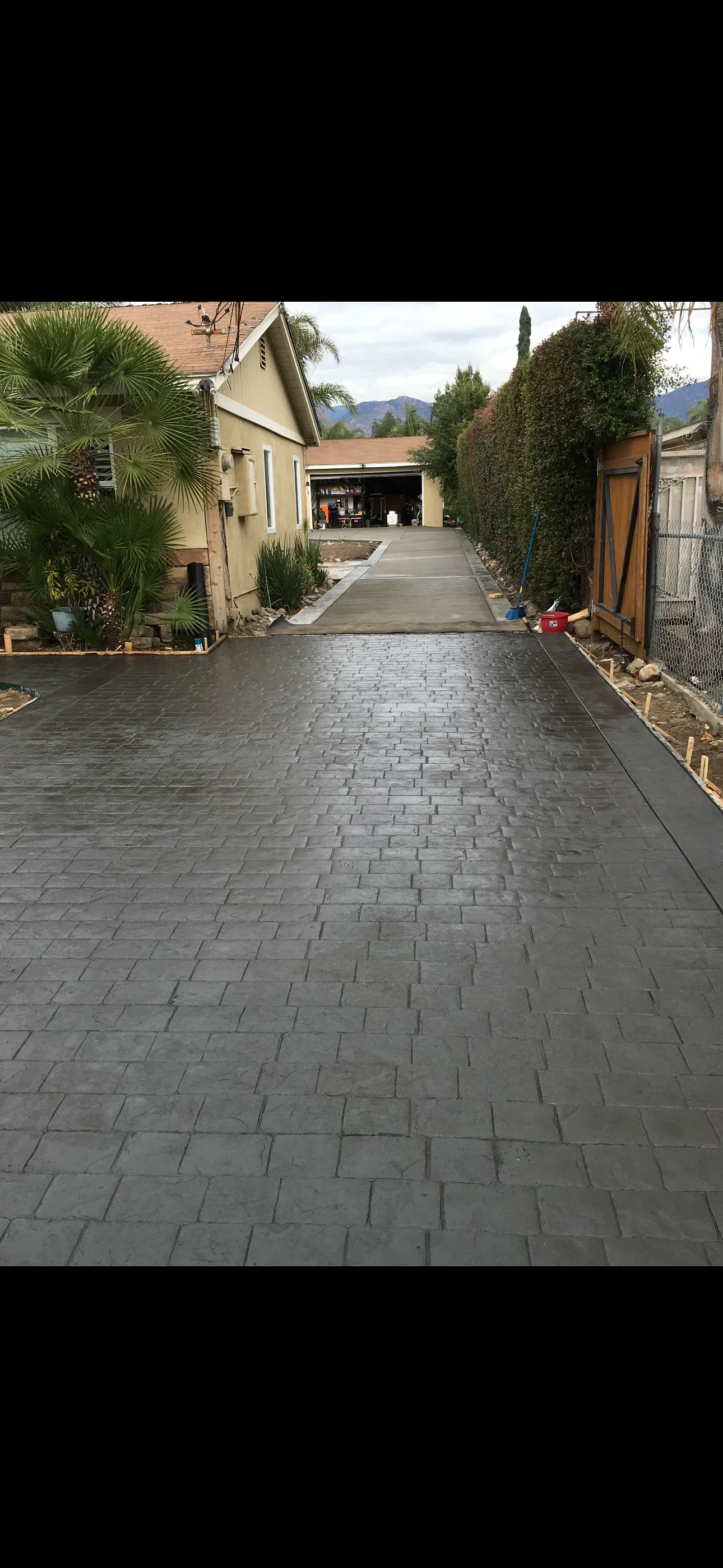 Dark gray stamped concrete driveway with slate pattern and broom-finished apron leading to garage