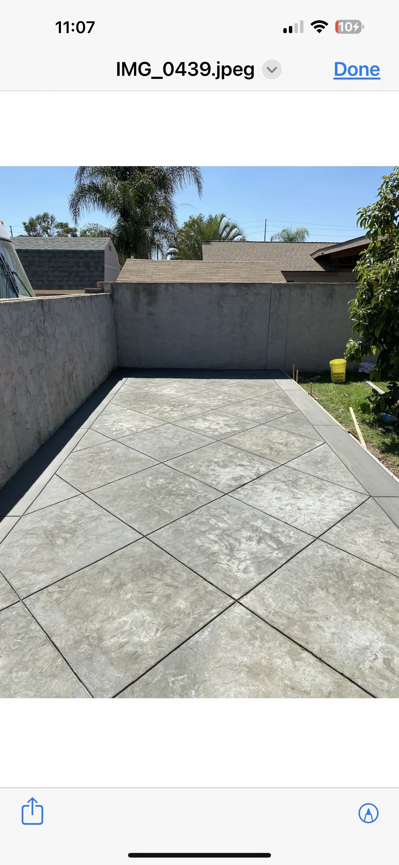Stamped concrete patio with large slate-pattern sections, dark joint lines, and gray antiqued finish against a block wall