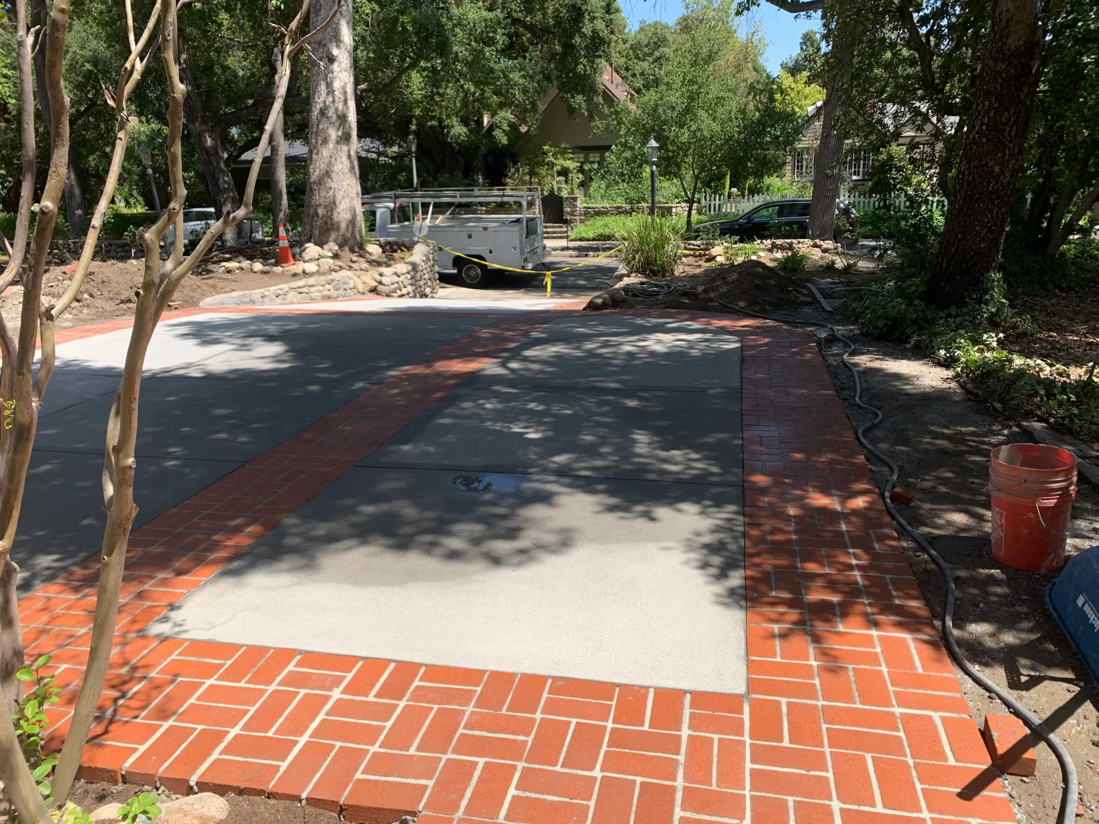Concrete driveway with saw-cut joints and red clay brick herringbone border under construction