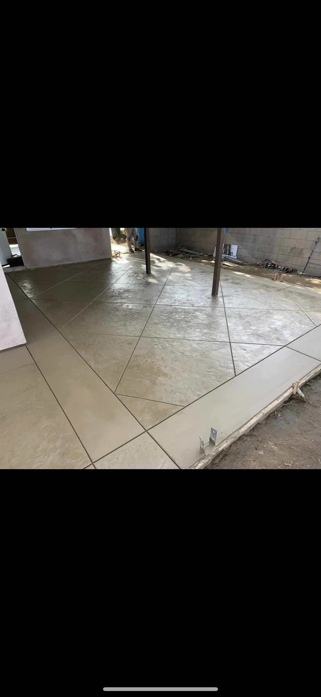 Stamped concrete patio with taupe slate texture, diagonal saw-cut joints, and smooth concrete border