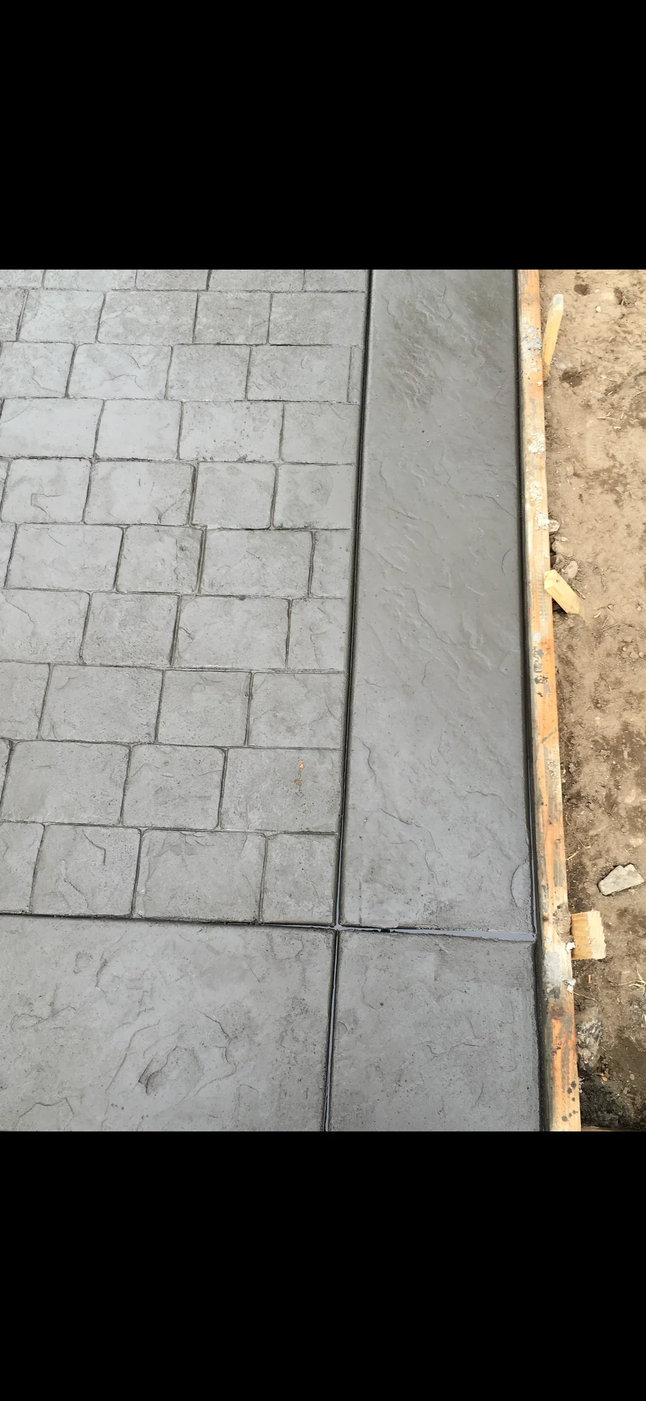 Gray stamped concrete with ashlar stone pattern and flagstone-textured slab beside wood form boards