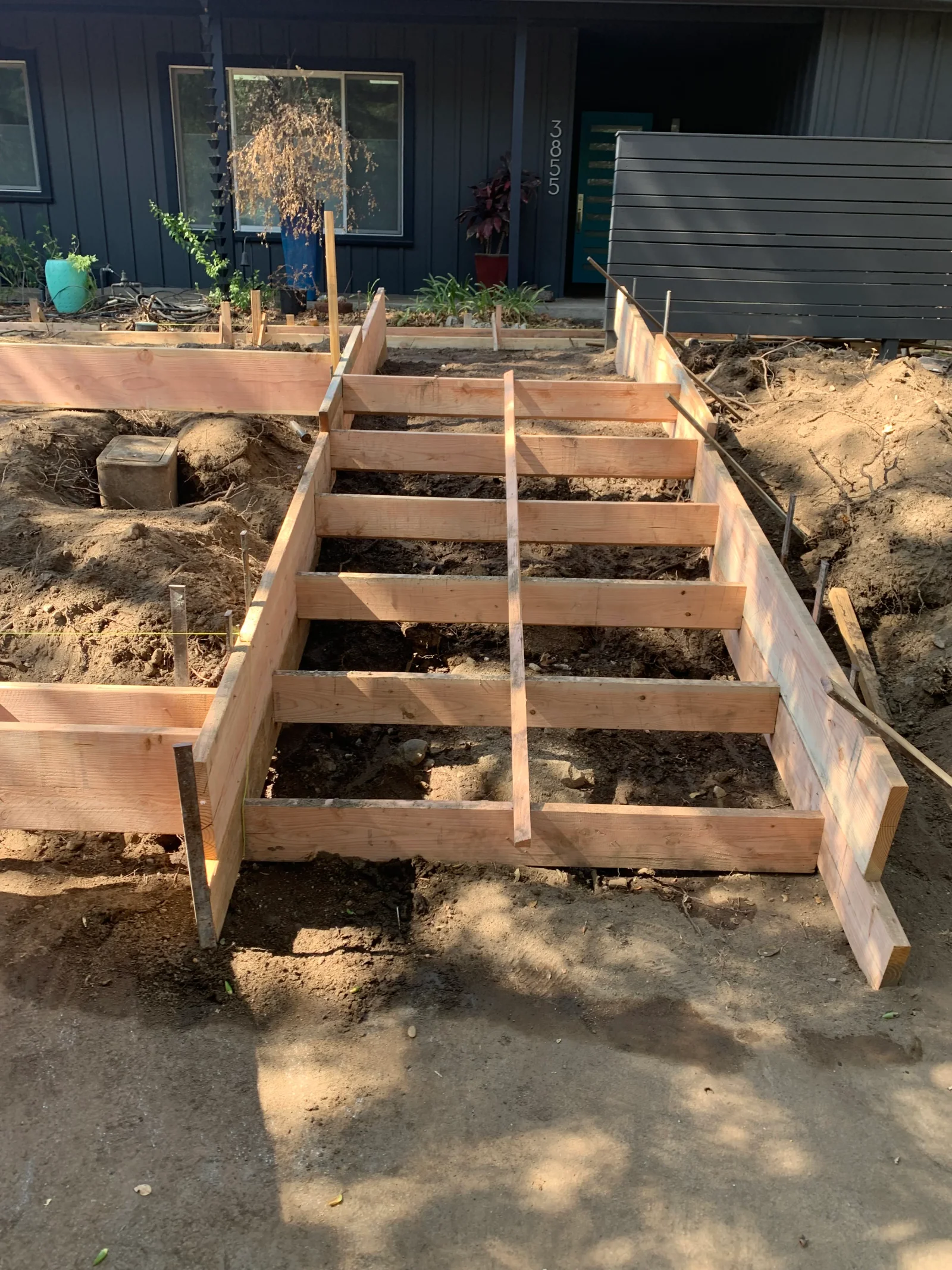 Wood form boards and interior cross-bracing staked in excavated soil for a concrete slab pour
